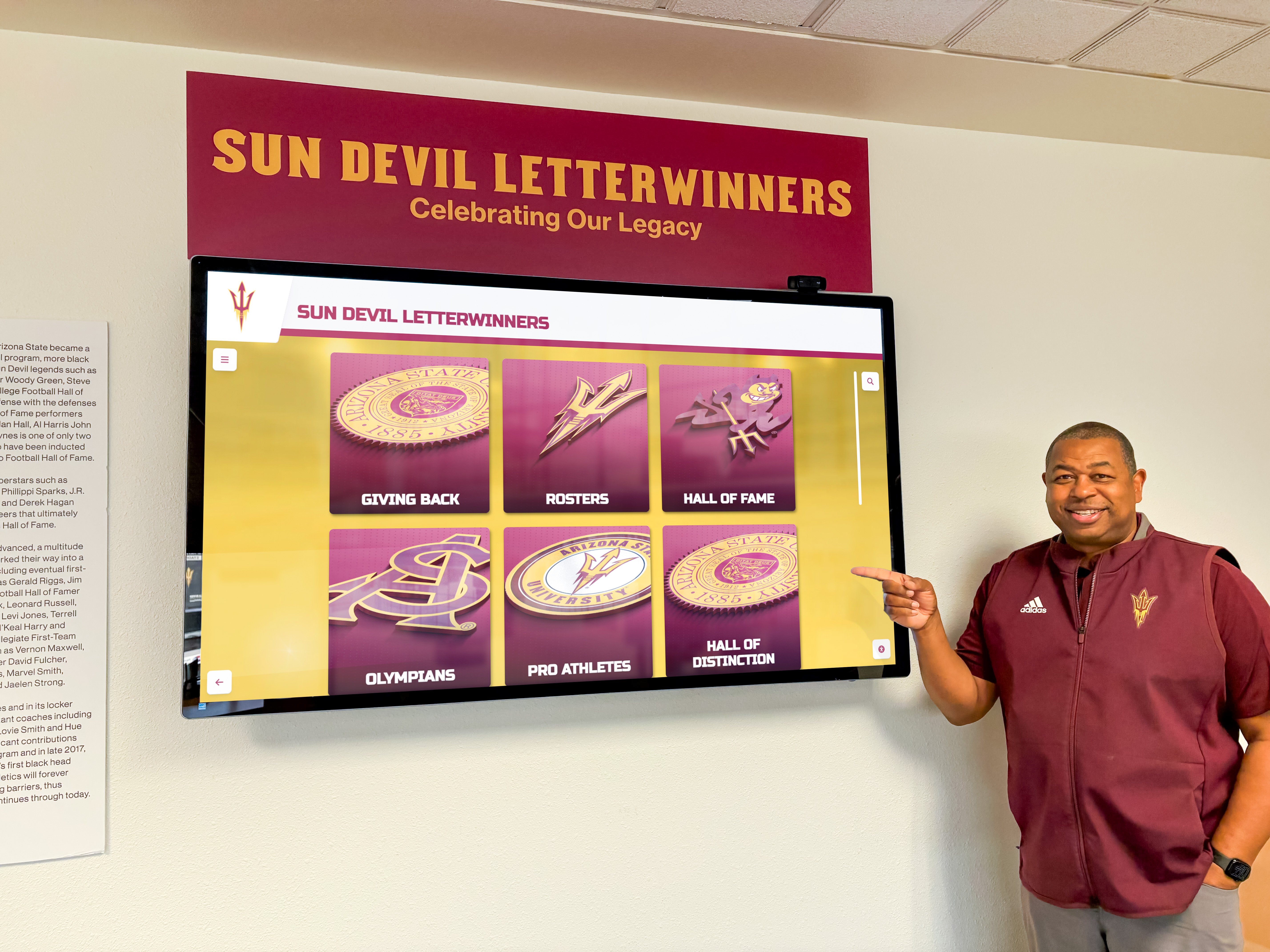 Staff member showing digital wall of fame features Administrator demonstrating interactive recognition capabilities